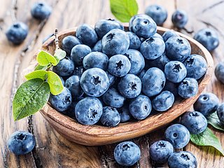 Heidelbeeren liegen in einer Holzschale. 