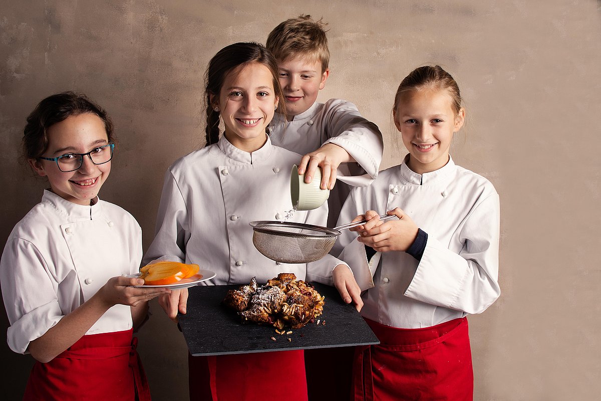 Vier Kinder mit einer Platte Essen in der Hand