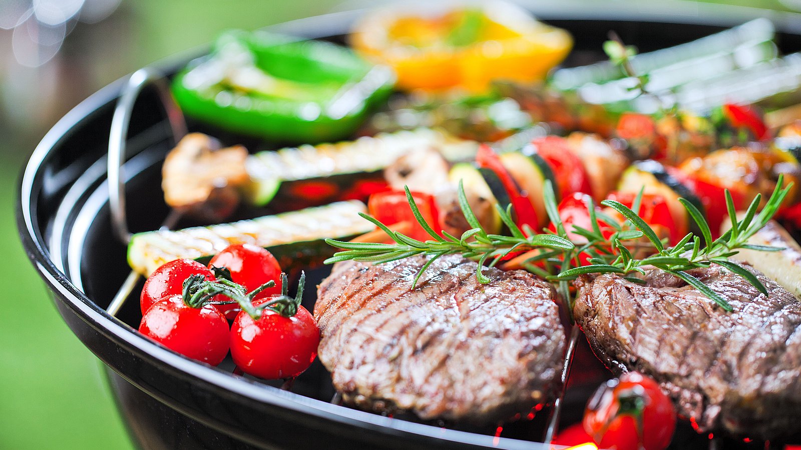 Fleisch und Gemüse liegen auf einem Grill. 