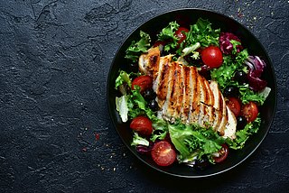 Gegrilltes Hähnchen auf grünem Salat und Tomaten