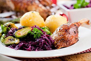 Teller mit Weihnachtsmenü, Rotkohl, Klöße, Rosenkohl und Gänsekeule